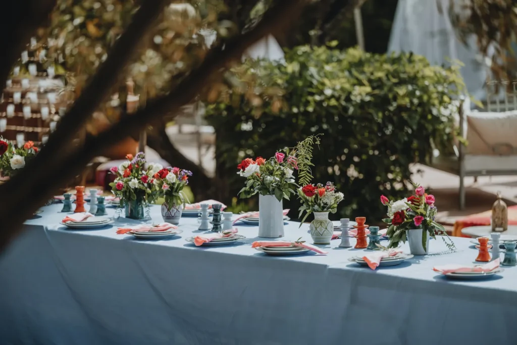Table de mariage dressee sous les oliviers, nappe bleue et bouquets