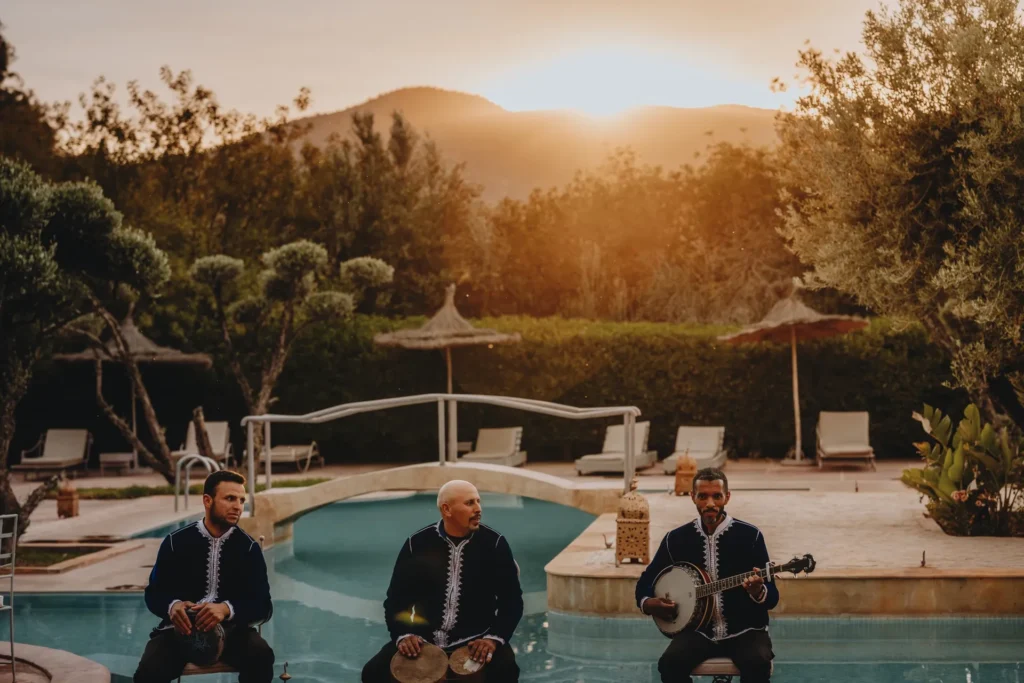 Trois musiciens en tenue traditionnelle au bord du bassin au coucher du soleil
